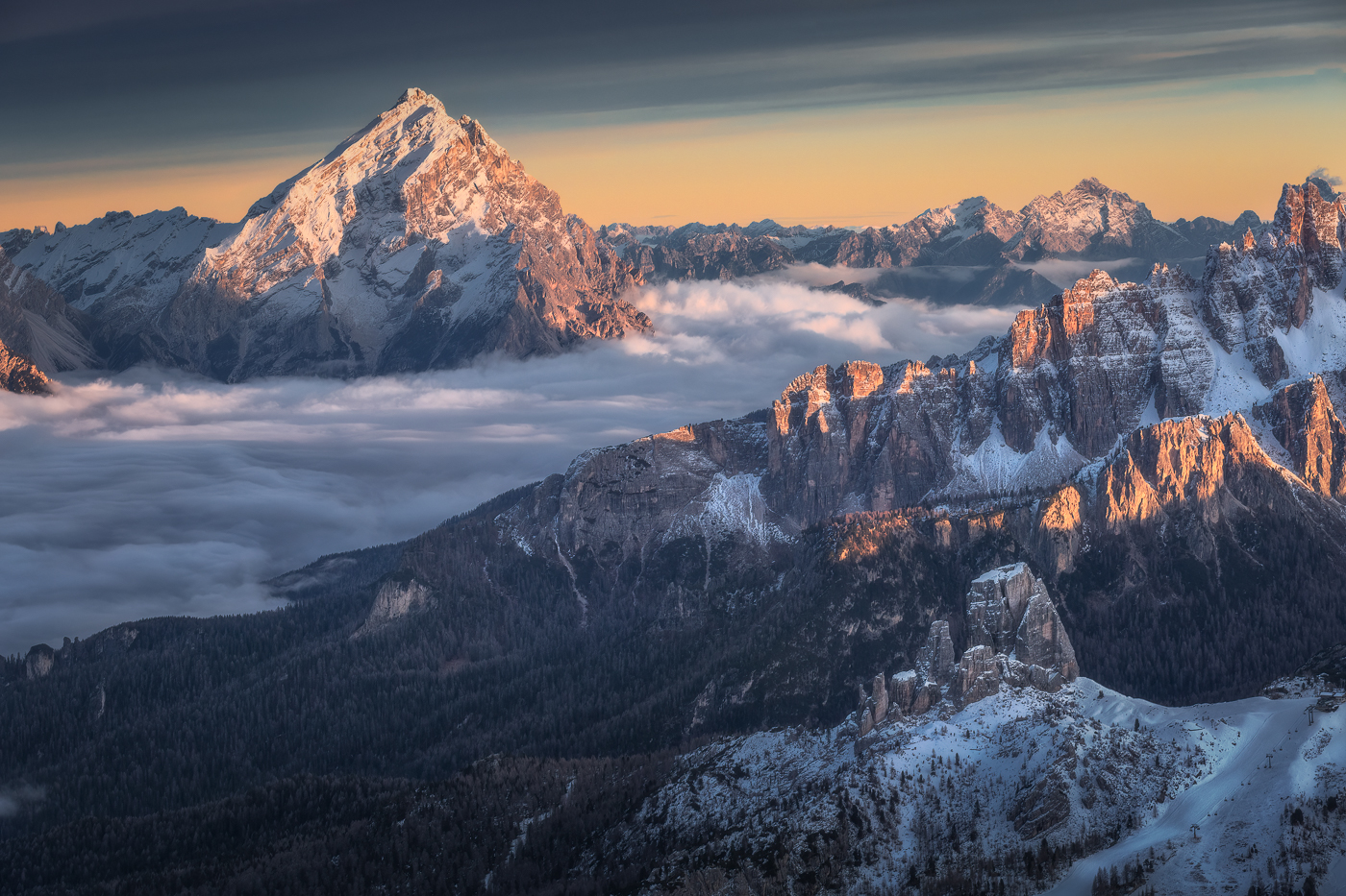 Estese e scure nubi alte danno risalto alle tonalità calde che accendono il Re delle Dolomiti, il monte Antelao. La Valle del Boite, invece, è già sommersa dall’oscurità. Dolomiti Ampezzane, Italia.