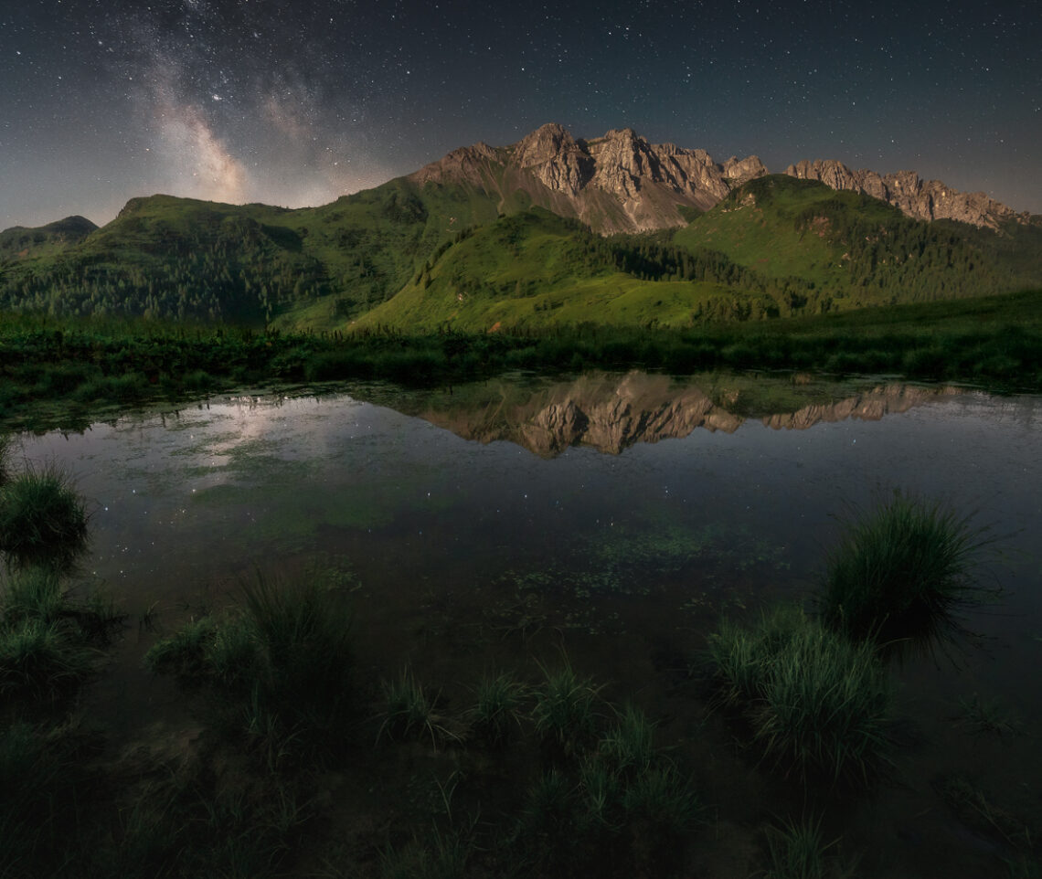 La Luna sorge, alle mie spalle, prendendosi la scena sul paesaggio. Ma non in cielo, dove resiste ancora, eterna, la Via Lattea. Alpi Carniche, Italia.