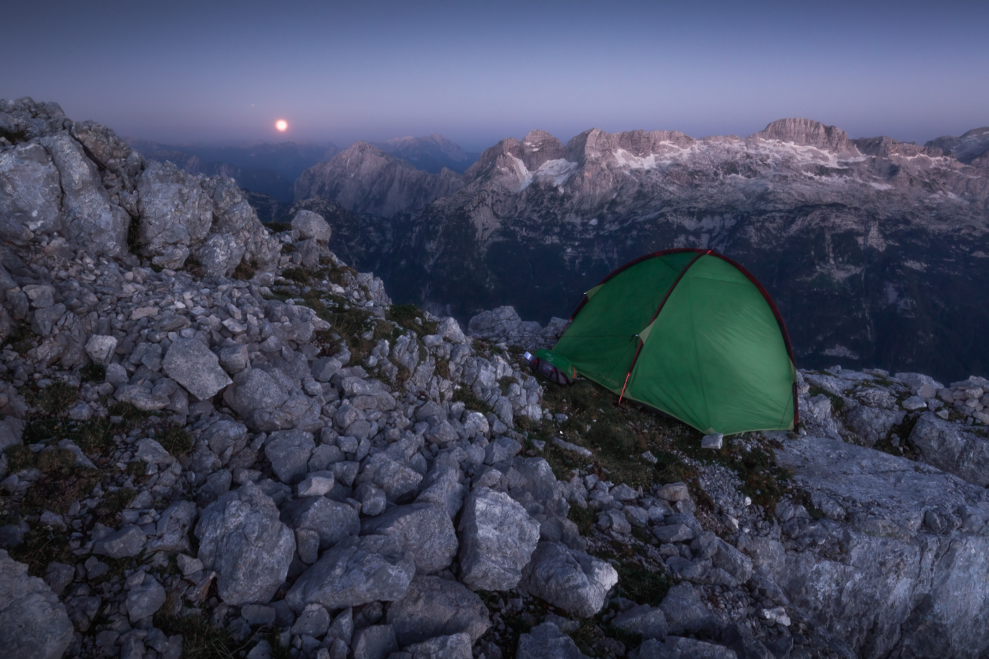 Ora blu e Luna piena sulle creste rocciose delle Alpi Giulie, Italia.