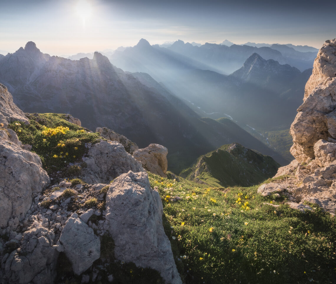 In piena estate, subito dopo l’alba, il Sole si eleva velocemente fra le vette delle Alpi Giulie, Italia.