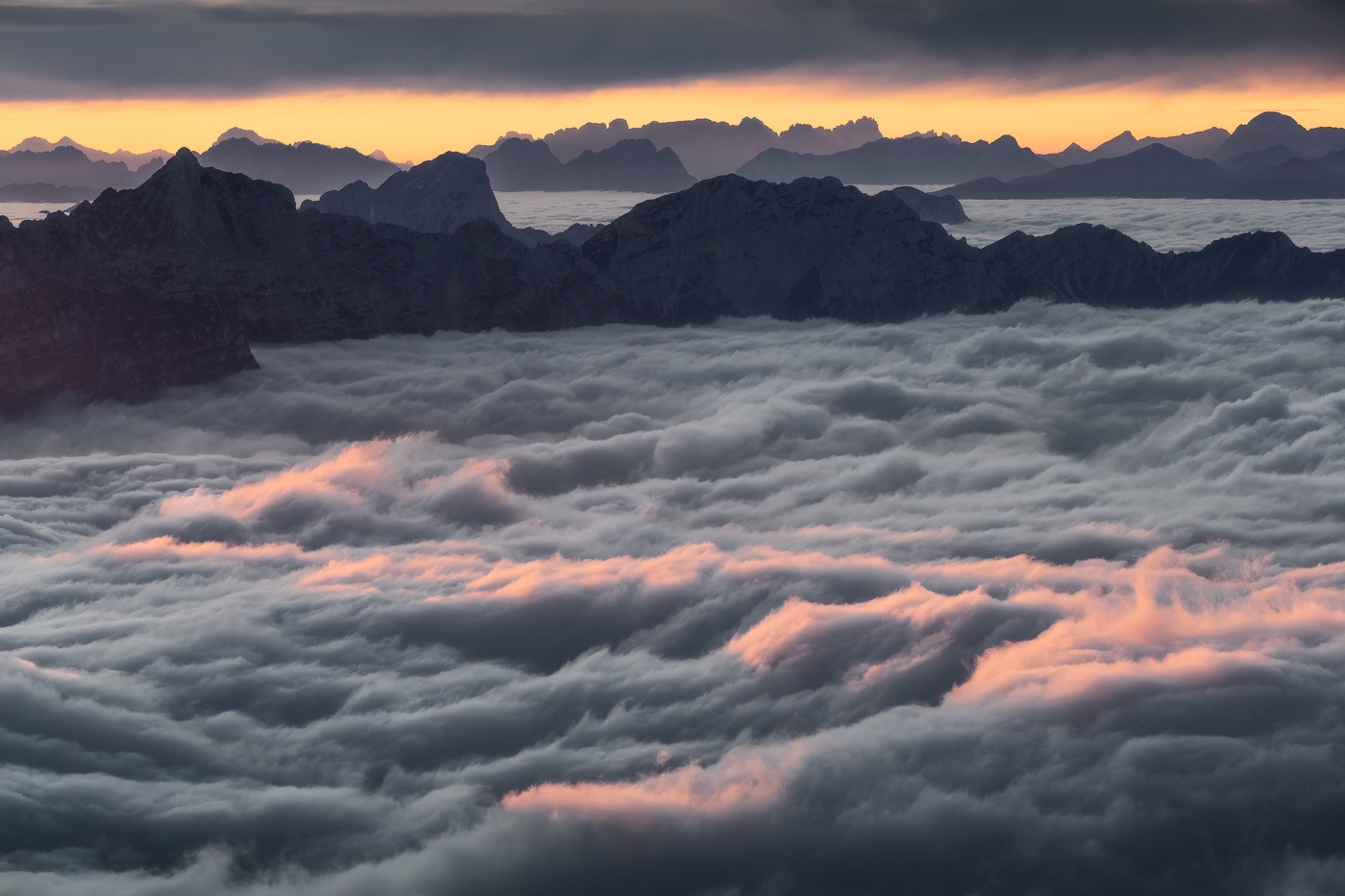 Terra! I profili delle Dolomiti di Sesto, sullo sfondo, risaltano, inconfondibili, navigando su questo mare di nuvole. Alpi Carniche e Dolomiti, Italia.
