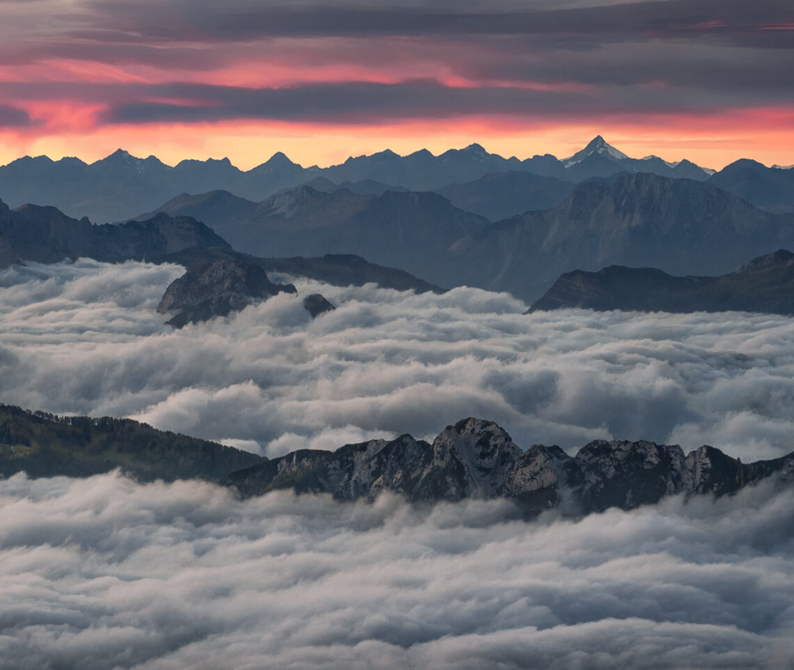 Un mare di nubi mi separa dal mondo rumoroso delle basse quote, aprendomi verso un cielo silenzioso colorato dal fuoco. Alpi Giulie, Italia.