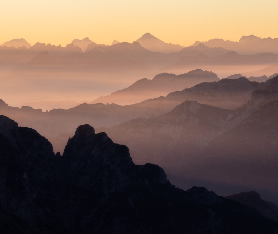 Il vapore acqueo presente nei bassi strati dell’atmosfera accende il tramonto: la bellezza si rivela. Alpi Carniche e Dolomiti, Italia.