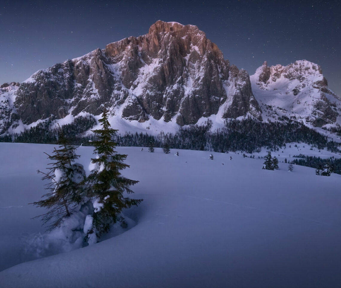 L’ora blu lascia il posto alla notte, che abbraccia un paesaggio silenzioso dalle atmosfere artiche. Alpi Carniche, Italia.