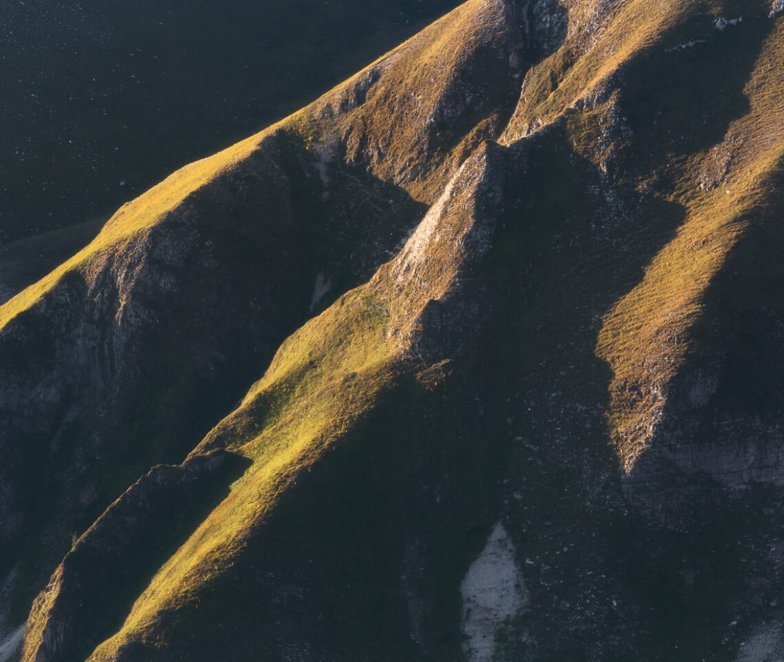 Artigli lucenti. All’alba, strappi di luce accendono i versanti ancora bui dei Monti Sibillini, Italia.