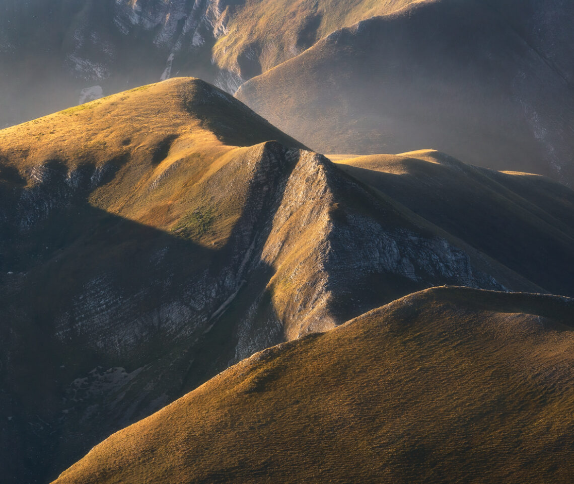 Un tessuto vellutato riveste i versanti dei Monti Sibillini accarezzati dai caldi raggi solari dell’alba. Parco Nazionale dei Monti Sibillini, Italia.