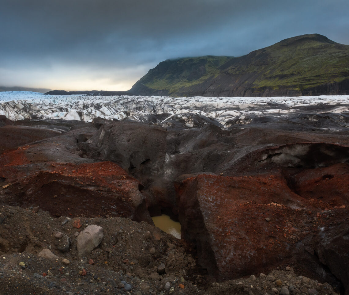 Sedimenti variopinti rivestono i blocchi di ghiaccio della fronte del ghiaccio Svínafellsjökull. In continuo, percettibile, movimento. Vatnajökull National Park, Islanda.