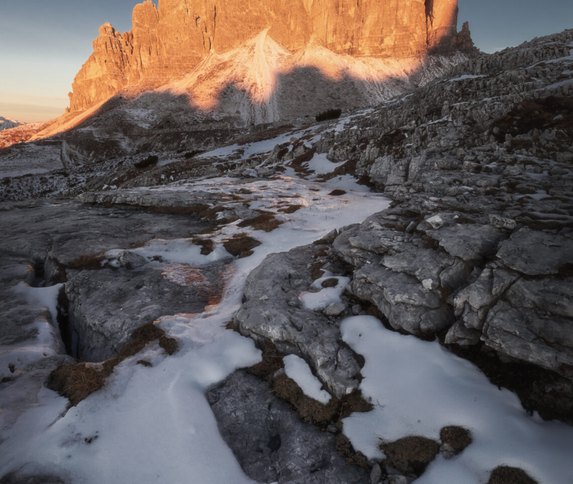 Fiamme ardenti riscaldano un paesaggio ancora immerso in un gelido stallo temporale. Parco Naturale Tre Cime, Dolomiti di Sesto, Italia.