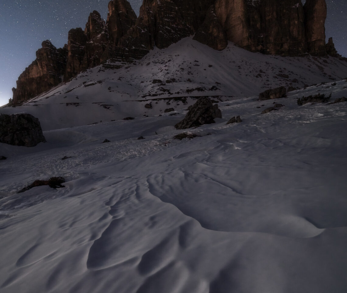 Le Tre Cime di Lavaredo si elevano verso le stelle dalla gelida coltre bianca invernale. Parco Naturale Tre Cime, Dolomiti di Sesto, Italia.