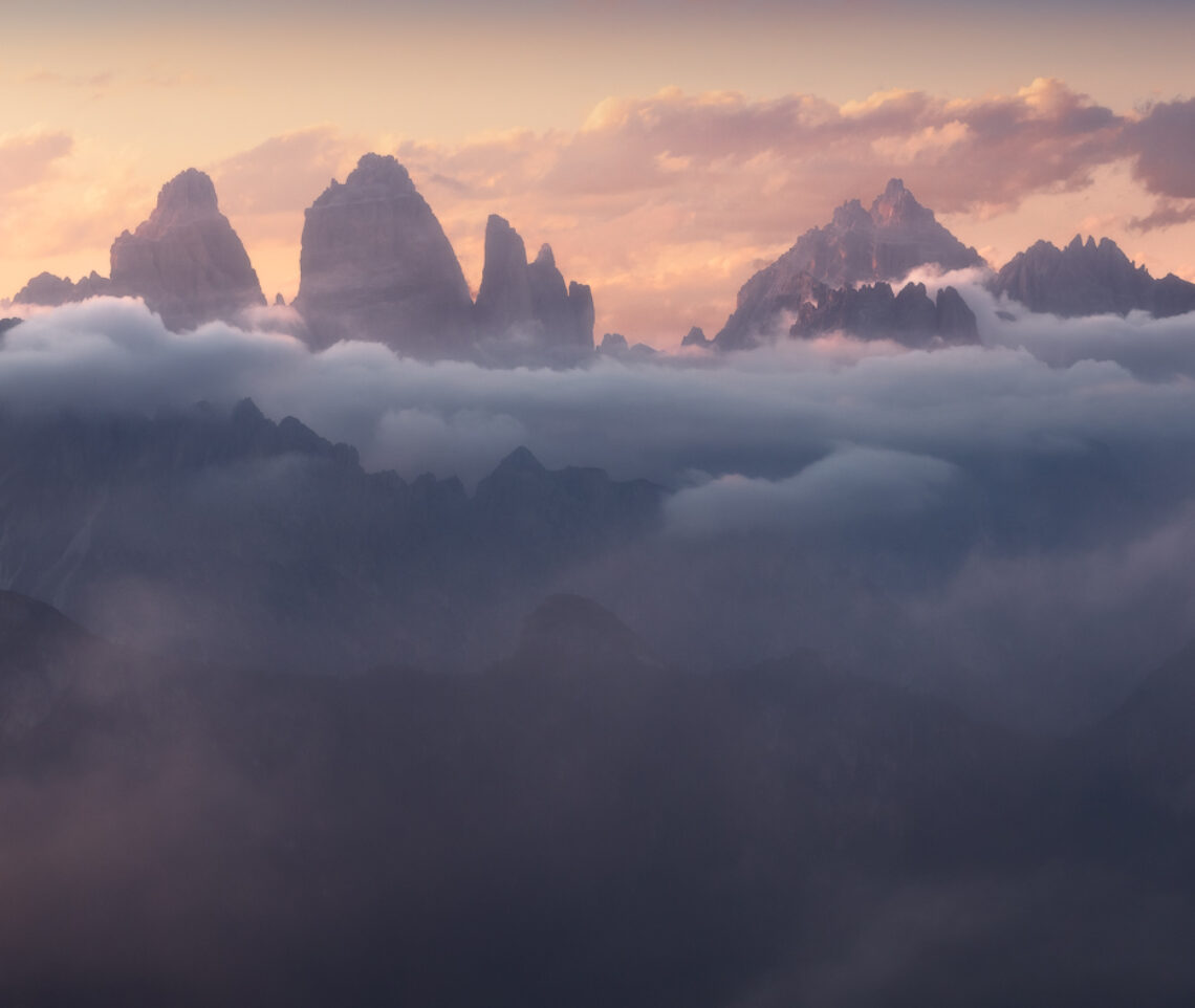 Geometrie inequivocabili emergono da un oceano ovattato durante un magico tramonto. Dolomiti di Sesto dal Gruppo delle Marmarole, Italia.