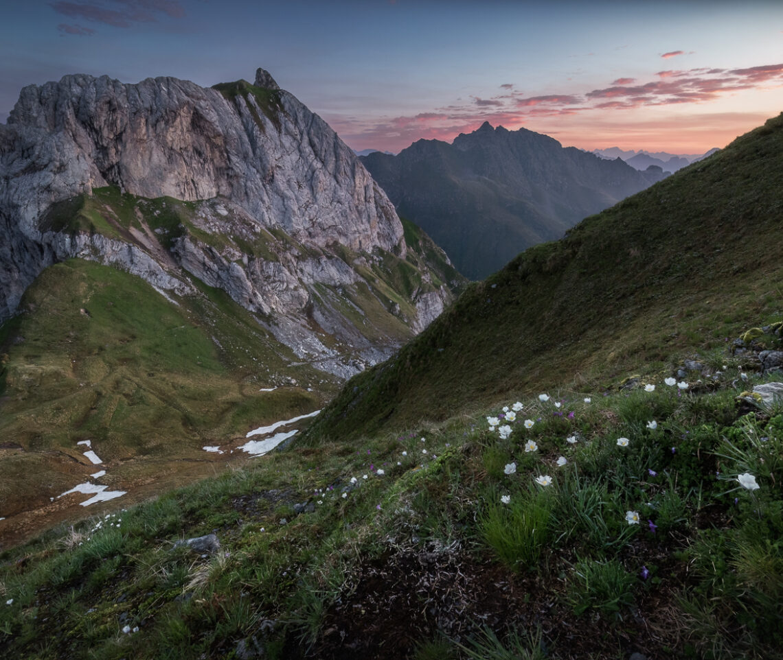 L’ora blu del mattino lascia il palcoscenico alle tonalità rosate della prima luce del Sole all’orizzonte. Alpi Carniche, Italia.