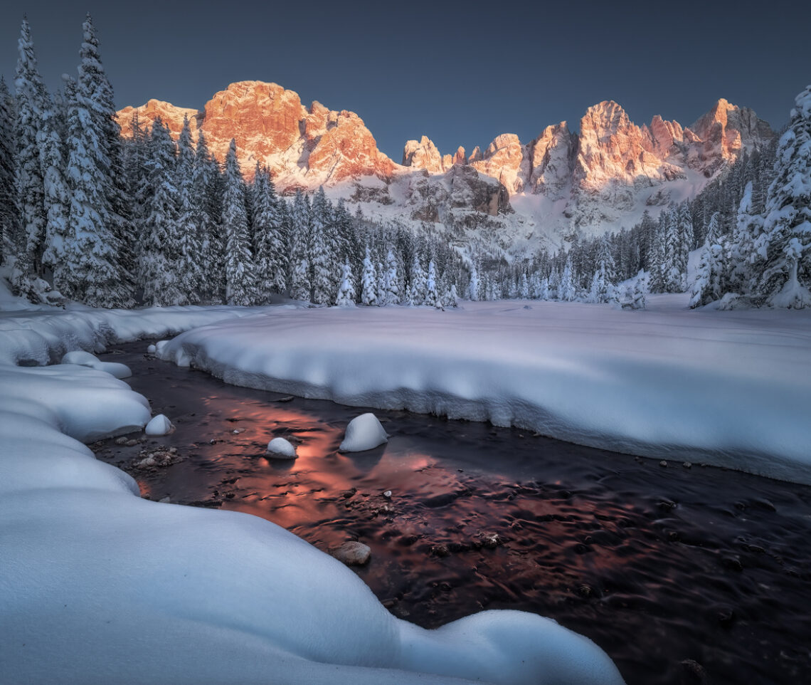 L’ultima luce del tramonto infiamma la terra e l’acqua, dando vita a uno spettacolo senza eguali. Parco Naturale Paneveggio Pale di San Martino, Italia.