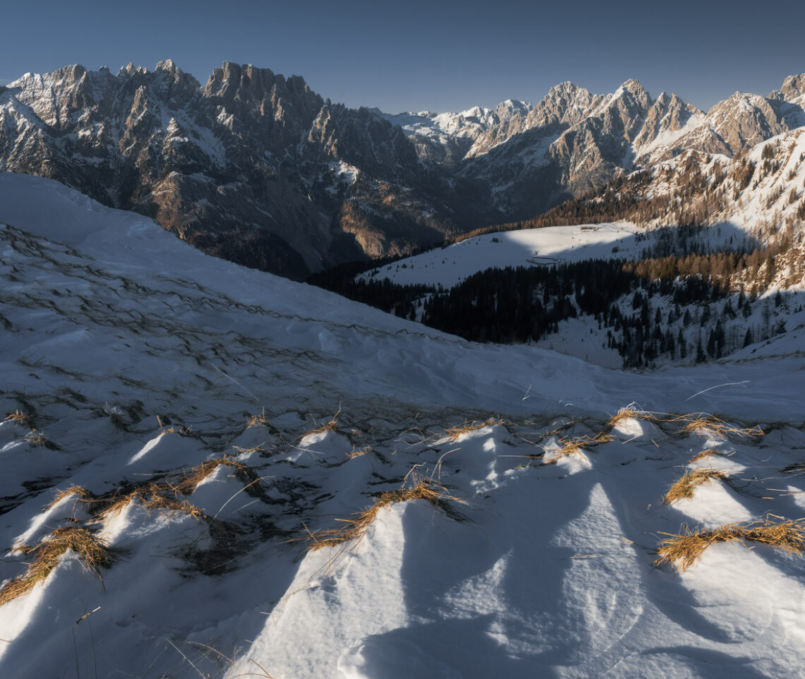 Raffiche di vento a oltre 100 km/h hanno modellato per giornate intere il manto nevoso che riveste i sinuosi rilievi al cospetto delle Dolomiti Pesarine. Alpi Carniche, Italia.